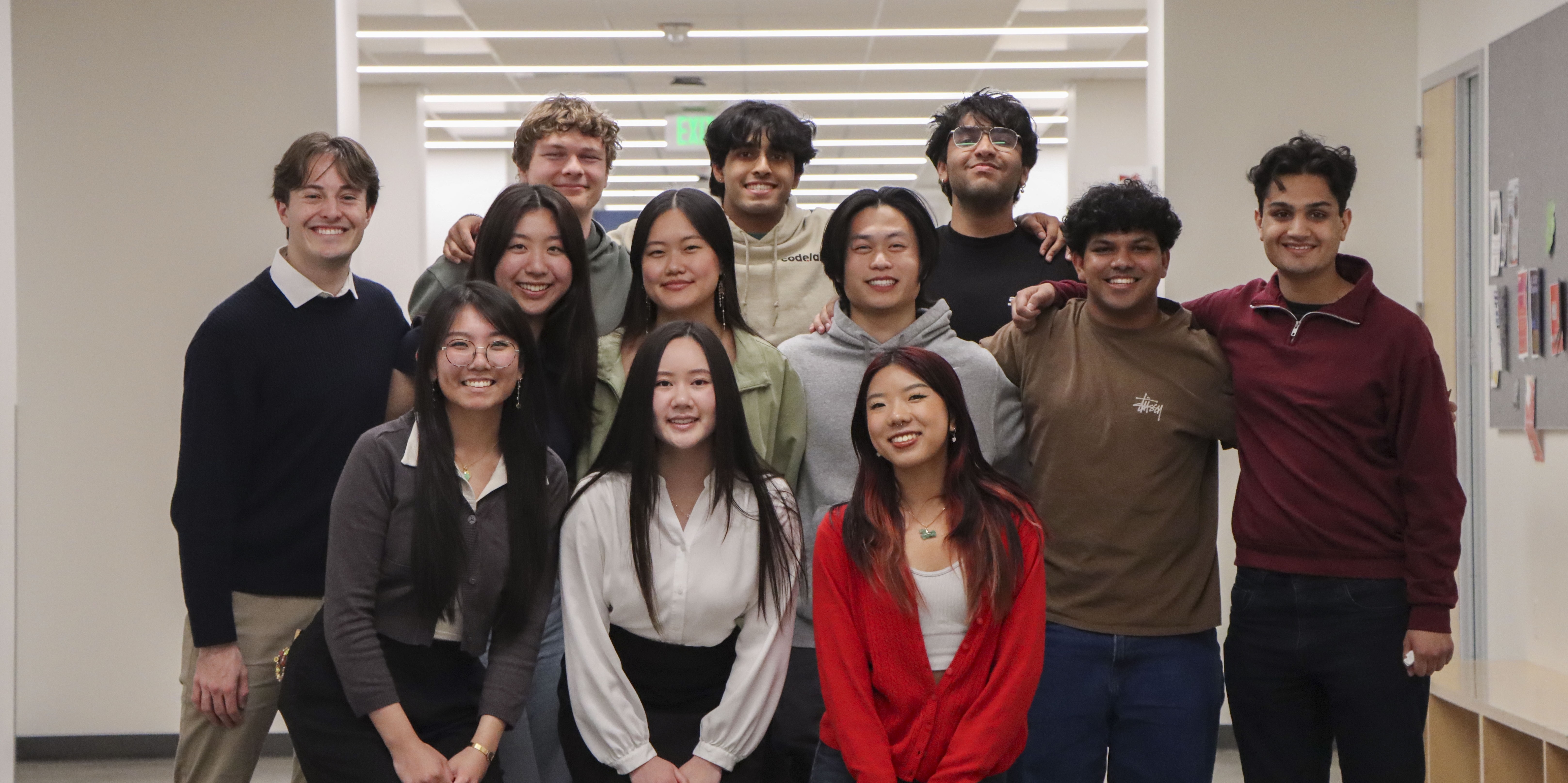 A group of female and male college students stand together in three roles.